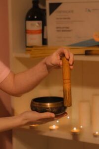 Hands holding a Tibetan singing bowl during a meditation ritual indoors.